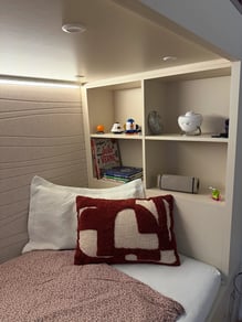 Útulný interiér dětského pokoje s postelí a policemi.